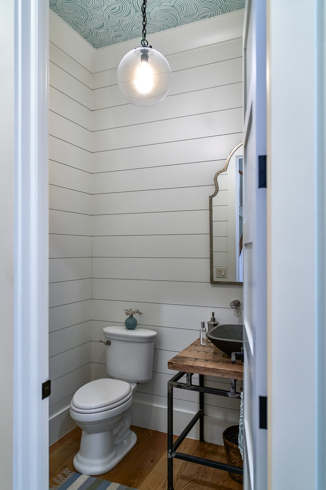 Modelo de cuarto de baño marinero de tamaño medio con paredes blancas, suelo de madera oscura, aseo y ducha, encimera de madera, suelo marrón y encimeras marrones