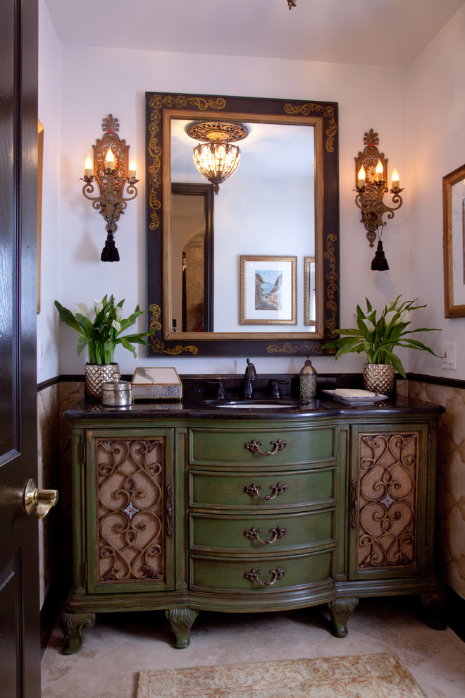 Inspiration for a small mediterranean cloakroom in Orange County with freestanding cabinets, green cabinets, a one-piece toilet, beige tiles, travertine tiles, beige walls, travertine flooring, a submerged sink, granite worktops, beige floors, black worktops and a freestanding vanity unit.