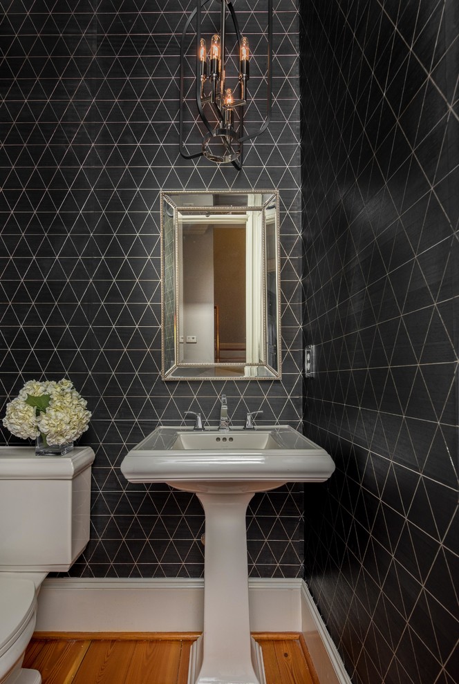 Modelo de cuarto de baño contemporáneo pequeño con sanitario de una pieza, paredes negras, suelo de madera en tonos medios, aseo y ducha, lavabo con pedestal y suelo marrón