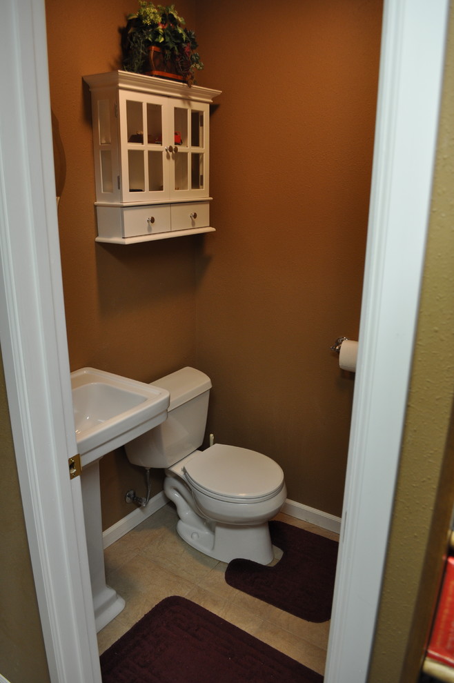 Idéer för att renovera ett vintage badrum, med ett piedestal handfat, en toalettstol med separat cisternkåpa, beige kakel, porslinskakel, bruna väggar, klinkergolv i porslin, luckor med glaspanel och vita skåp
