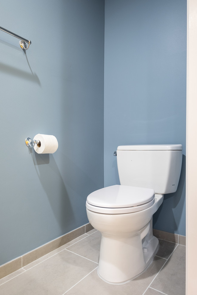Aménagement d'un WC et toilettes classique de taille moyenne avec un placard avec porte à panneau encastré, des portes de placard blanches, WC séparés, un carrelage blanc, des carreaux de céramique, un mur bleu, un sol en carrelage de porcelaine, un lavabo encastré et un plan de toilette en quartz modifié.