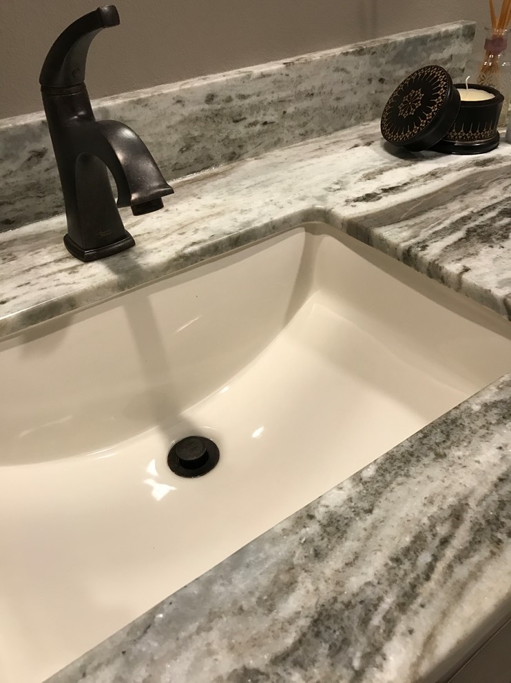 Exotisk inredning av ett stort grå grått badrum med dusch, med släta luckor, bruna skåp, en öppen dusch, en toalettstol med hel cisternkåpa, beige kakel, stenhäll, grå väggar, klinkergolv i keramik, ett undermonterad handfat, granitbänkskiva, beiget golv och med dusch som är öppen