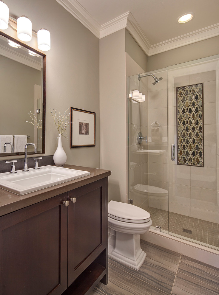 Example of a classic gray tile porcelain tile bathroom design in Seattle with a drop-in sink, furniture-like cabinets, dark wood cabinets, quartz countertops, gray walls and a two-piece toilet
