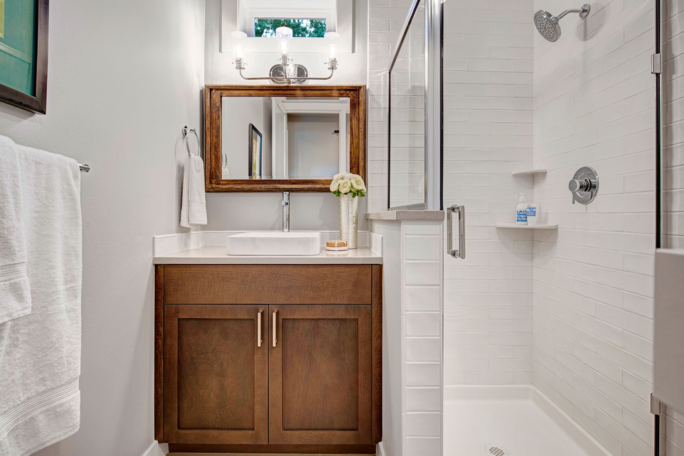 Bild på ett amerikanskt vit vitt badrum med dusch, med bruna skåp, en hörndusch, en toalettstol med hel cisternkåpa, vit kakel, keramikplattor, grå väggar, klinkergolv i keramik, ett fristående handfat, bänkskiva i kvartsit och dusch med gångjärnsdörr