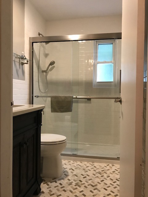 Пример оригинального дизайна: маленькая ванная комната в стиле неоклассика (современная классика) с фасадами с выступающей филенкой, темными деревянными фасадами, душем в нише, унитазом-моноблоком, белой плиткой, керамической плиткой, коричневыми стенами, полом из мозаичной плитки, врезной раковиной, бежевым полом и душем с раздвижными дверями для на участке и в саду