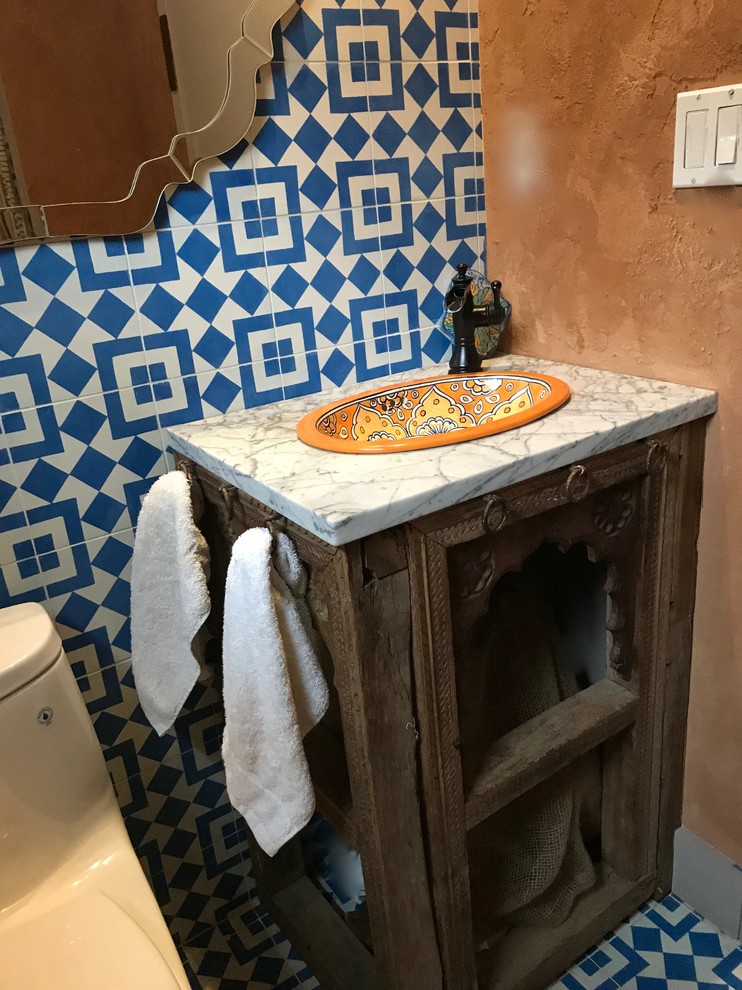 Immagine di una piccola stanza da bagno con doccia mediterranea con ante in legno bruno, doccia alcova, WC a due pezzi, piastrelle blu, piastrelle a mosaico, pareti arancioni, pavimento in cementine, lavabo da incasso, top in marmo, pavimento blu e doccia con tenda