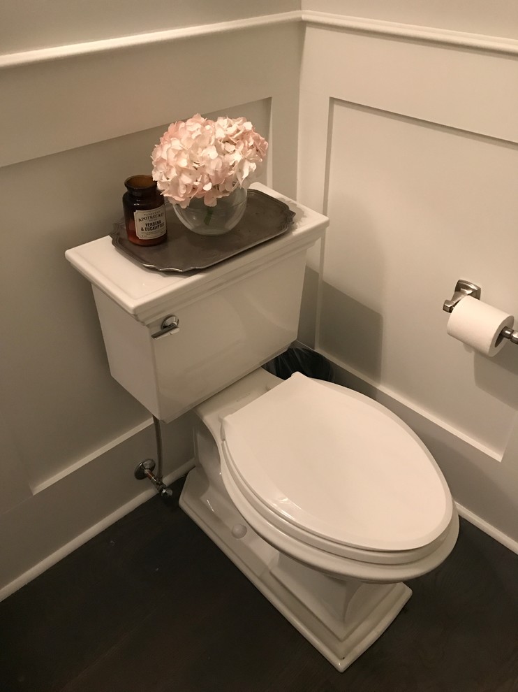 Foto på ett litet vintage toalett, med en toalettstol med separat cisternkåpa, grå väggar, mörkt trägolv, ett piedestal handfat och brunt golv