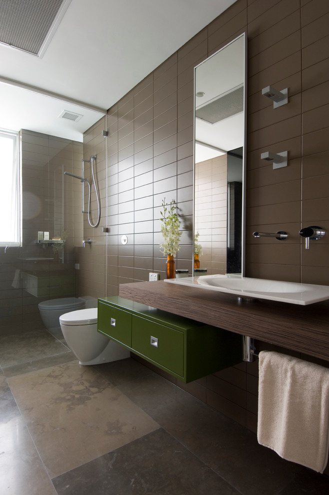 На фото: ванная комната в стиле модернизм с настольной раковиной, плоскими фасадами, зелеными фасадами, столешницей из дерева, душем без бортиков, коричневой плиткой, коричневыми стенами и коричневой столешницей