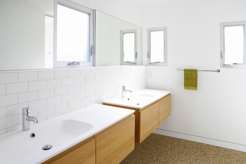 Идея дизайна: ванная комната в стиле модернизм с монолитной раковиной, плоскими фасадами, светлыми деревянными фасадами, белой плиткой, плиткой кабанчик, белыми стенами и белой столешницей