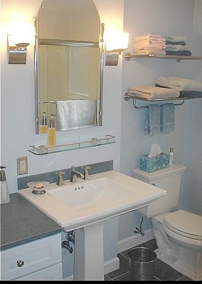 Medium sized contemporary ensuite bathroom in Boston with a two-piece toilet, grey tiles, open cabinets, white cabinets, a corner shower, blue walls, cement flooring, a pedestal sink and solid surface worktops.