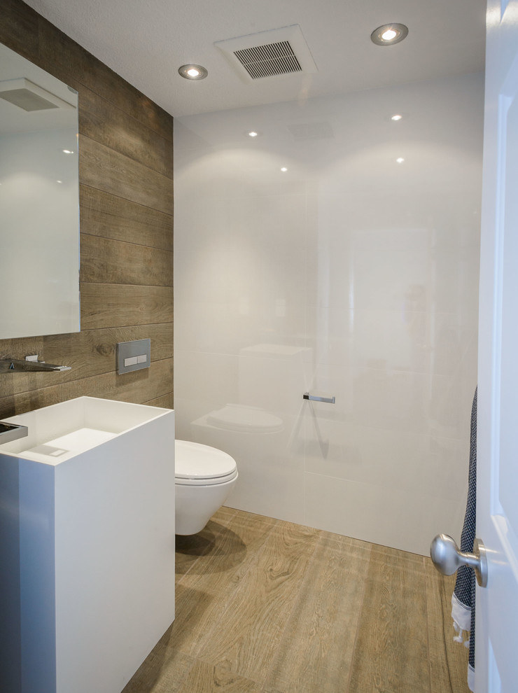 Example of a small minimalist 3/4 stone tile medium tone wood floor bathroom design in San Francisco with an integrated sink, a wall-mount toilet and beige walls