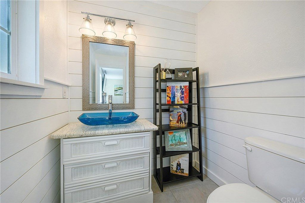 Foto de cuarto de baño campestre pequeño con armarios tipo mueble, puertas de armario blancas, paredes blancas, suelo de baldosas de cerámica, lavabo sobreencimera, encimera de granito y suelo gris
