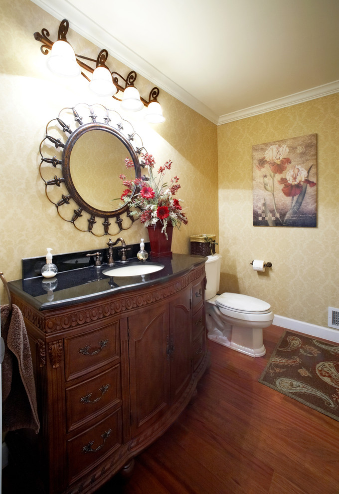 Cette image montre une salle de bain traditionnelle en bois foncé avec un lavabo encastré et un placard avec porte à panneau encastré.