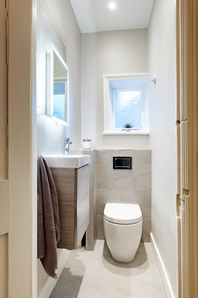 Идея дизайна: маленькая ванная комната в современном стиле с плоскими фасадами, светлыми деревянными фасадами, инсталляцией, серой плиткой, керамогранитной плиткой, серыми стенами, полом из керамогранита, накладной раковиной, серым полом, тумбой под одну раковину и подвесной тумбой для на участке и в саду