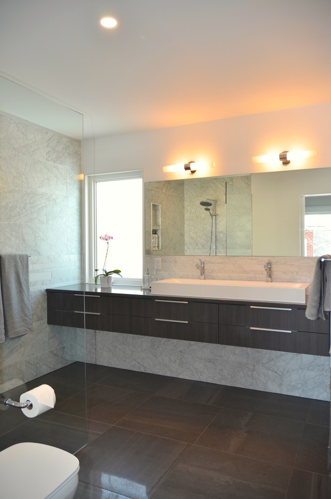 This is an example of a small contemporary ensuite bathroom in Ottawa with flat-panel cabinets, grey cabinets, an alcove shower, a one-piece toilet, beige tiles, porcelain tiles, white walls, porcelain flooring, an integrated sink, quartz worktops and a sliding door.