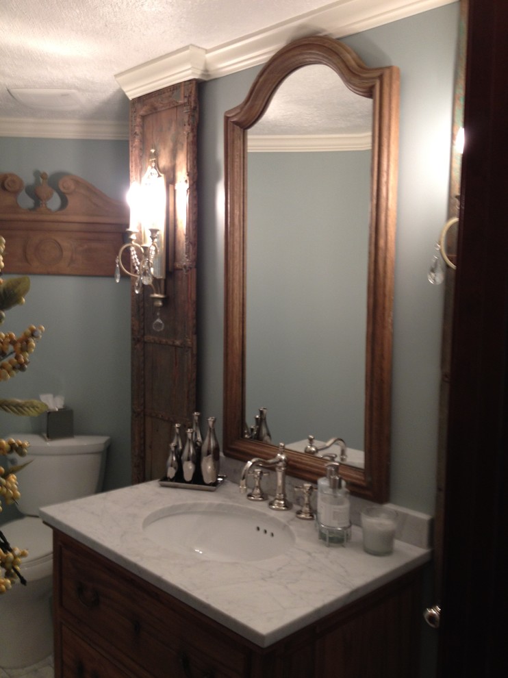 Idee per una stanza da bagno eclettica di medie dimensioni con lavabo sottopiano, consolle stile comò, ante con finitura invecchiata, top in marmo, WC a due pezzi, piastrelle bianche, piastrelle in pietra, pareti blu e pavimento in marmo