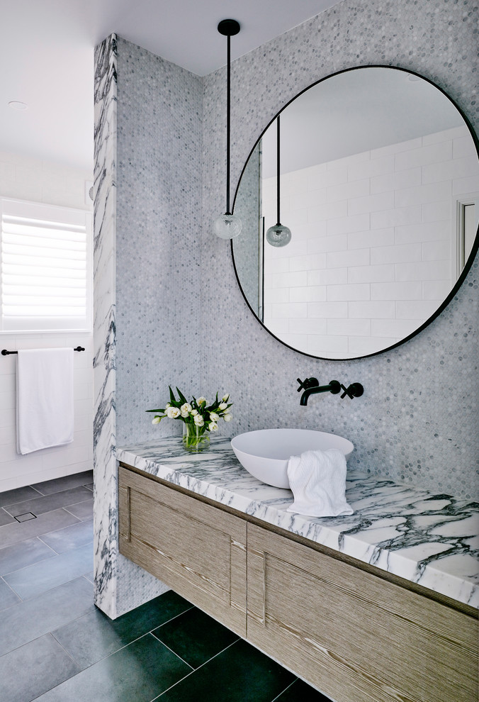 Réalisation d'une grande salle de bain design en bois brun avec un carrelage gris, du carrelage en marbre, un mur gris, un sol en carrelage de céramique, une vasque, un plan de toilette en marbre et un sol noir.