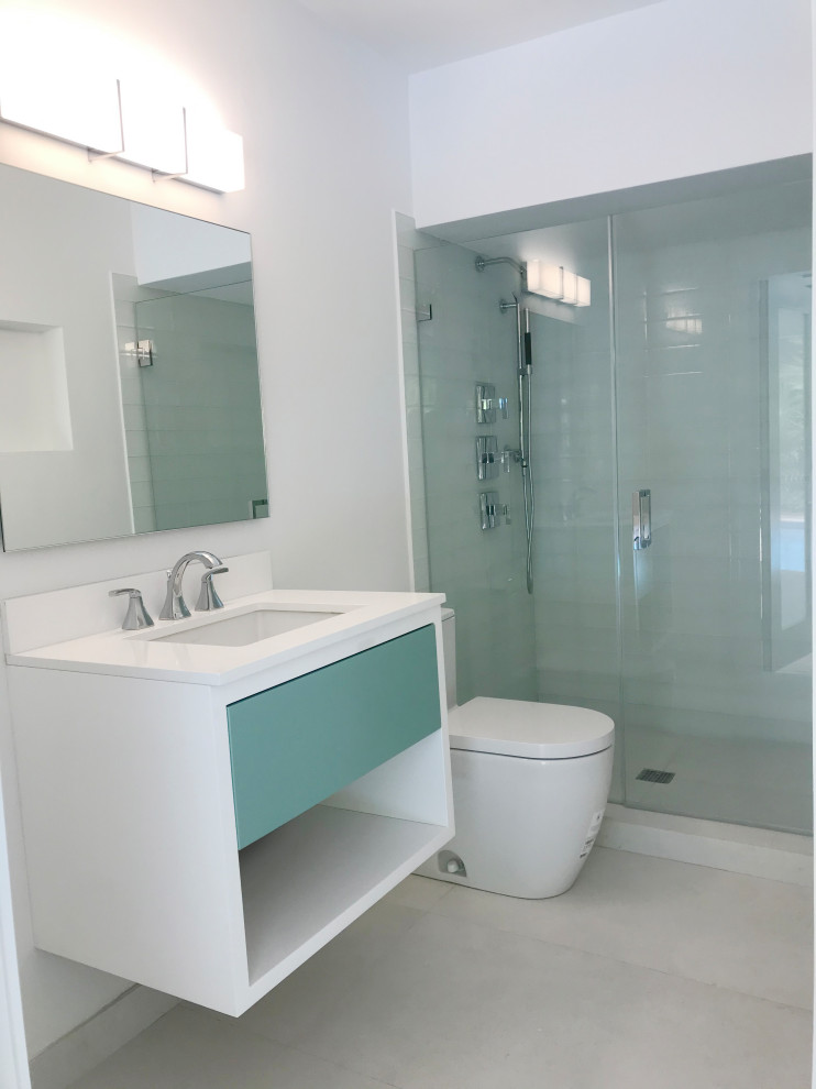 Пример оригинального дизайна: ванная комната среднего размера в стиле модернизм с плоскими фасадами, белыми фасадами, душем в нише, раздельным унитазом, белой плиткой, стеклянной плиткой, белыми стенами, полом из керамогранита, душевой кабиной, врезной раковиной, столешницей из искусственного кварца, белым полом, душем с распашными дверями, белой столешницей, тумбой под одну раковину и подвесной тумбой