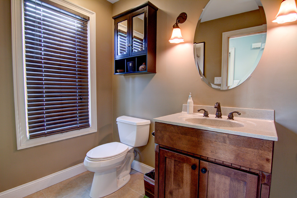Photo of a medium sized traditional family bathroom in New York with shaker cabinets, brown cabinets, a two-piece toilet, brown walls, ceramic flooring, an integrated sink, solid surface worktops, brown floors and white worktops.