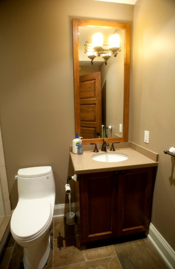 Esempio di un piccolo bagno di servizio stile americano con ante in stile shaker, ante in legno bruno, WC monopezzo, pareti beige, pavimento in ardesia, lavabo sottopiano e top in superficie solida