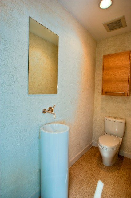 Photo of a small modern cloakroom in Los Angeles with a console sink, flat-panel cabinets, light wood cabinets, a one-piece toilet, beige tiles, ceramic tiles, white walls and ceramic flooring.