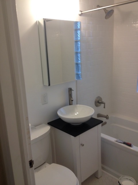 Exempel på ett litet klassiskt badrum, med ett fristående handfat, släta luckor, vita skåp, granitbänkskiva, ett badkar i en alkov, en toalettstol med separat cisternkåpa, vit kakel, keramikplattor, vita väggar och mosaikgolv