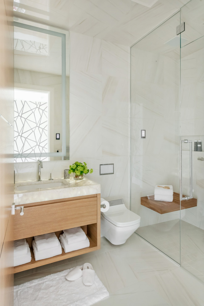 Modern inredning av ett stort svart svart badrum med dusch, med släta luckor, svarta skåp, en kantlös dusch, en vägghängd toalettstol, flerfärgad kakel, marmorkakel, flerfärgade väggar, klinkergolv i porslin, ett undermonterad handfat, marmorbänkskiva och vitt golv