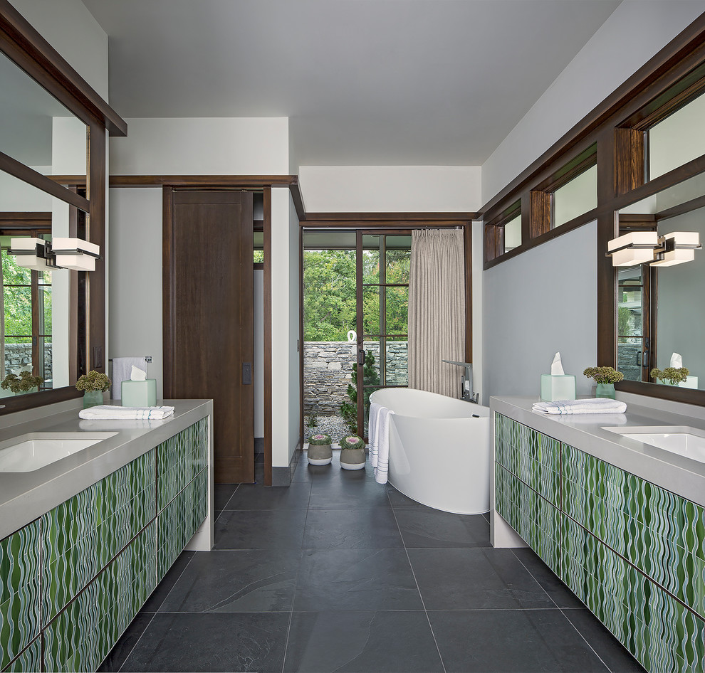 This is an example of a large contemporary ensuite bathroom in Detroit with green cabinets, a freestanding bath, grey walls, slate flooring, a submerged sink, engineered stone worktops and grey floors.