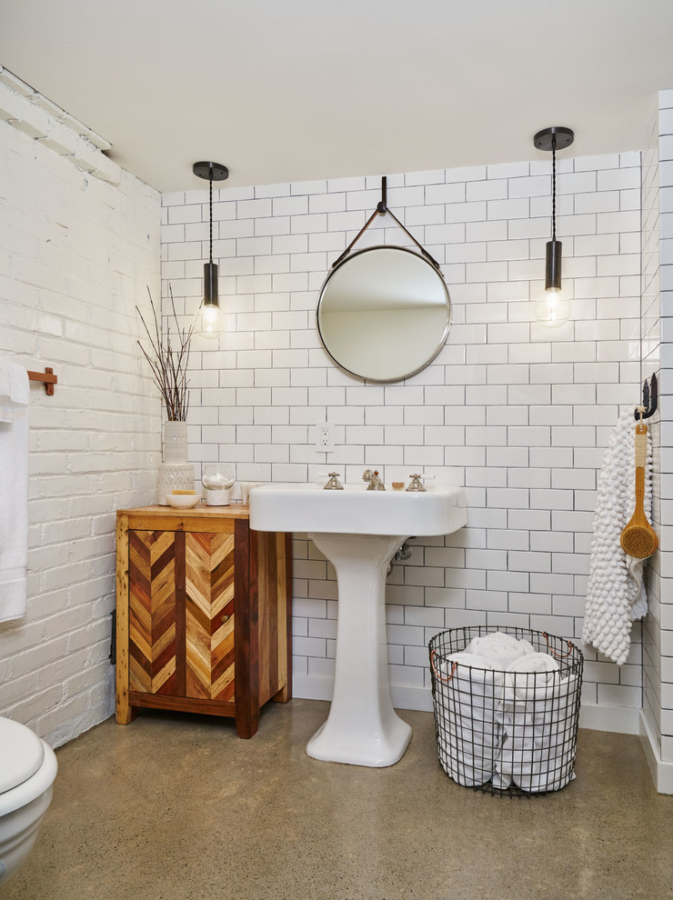 Foto på ett mellanstort eklektiskt badrum med dusch, med vit kakel, betonggolv, ett piedestal handfat, grått golv, vita väggar och tunnelbanekakel