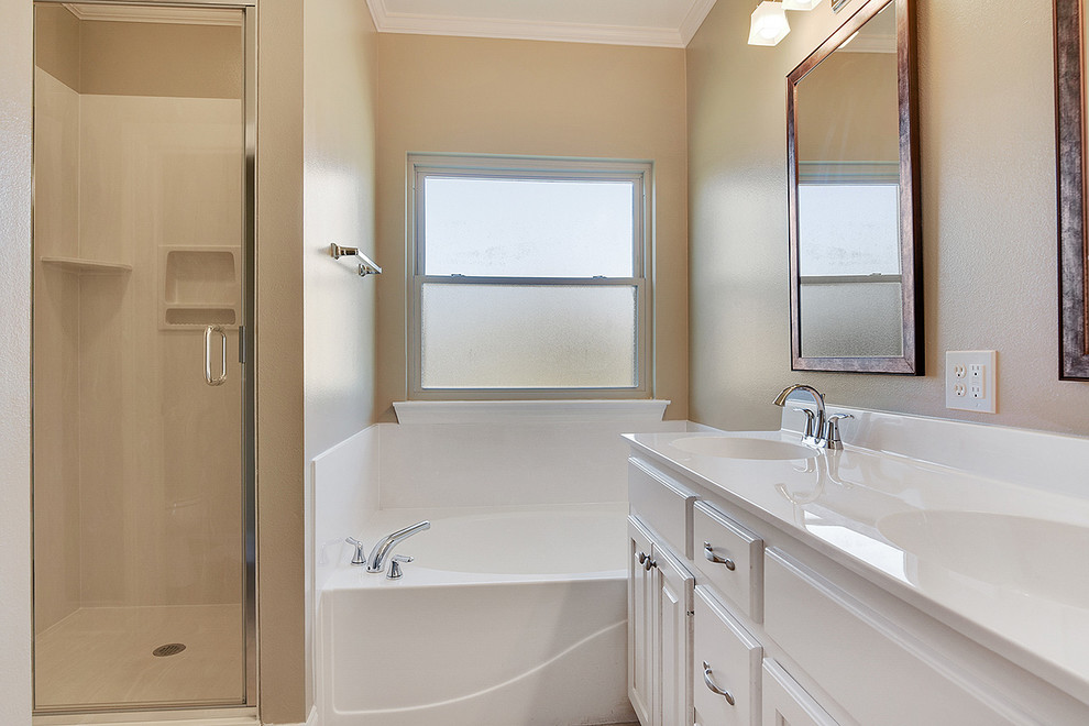 Foto de cuarto de baño principal clásico de tamaño medio con armarios con paneles con relieve, puertas de armario blancas, bañera empotrada, ducha empotrada, paredes beige, lavabo integrado y encimera de acrílico
