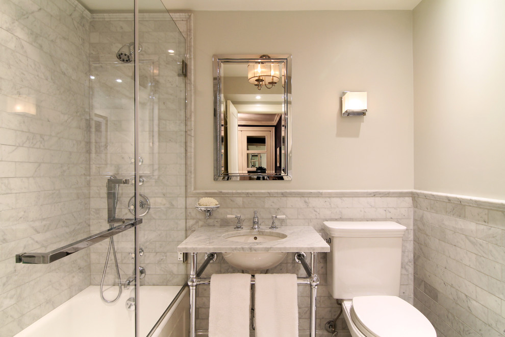Tub/shower combo - mid-sized traditional 3/4 gray tile and stone tile dark wood floor tub/shower combo idea in New York with a drop-in sink, marble countertops, an undermount tub, a one-piece toilet and white walls