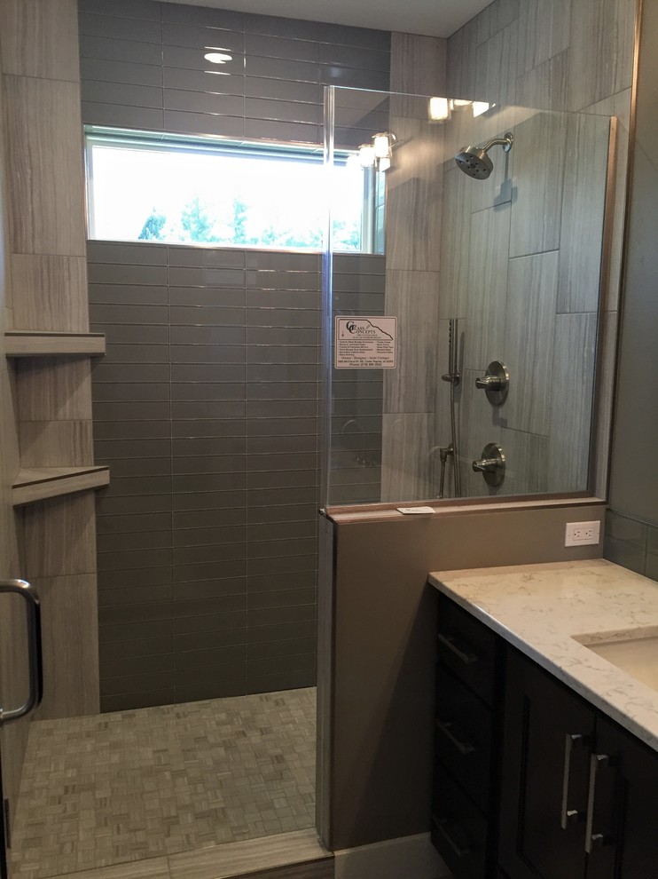 Medium sized contemporary shower room bathroom in Cedar Rapids with grey tiles, glass tiles, grey walls, flat-panel cabinets, black cabinets, a submerged sink and quartz worktops.