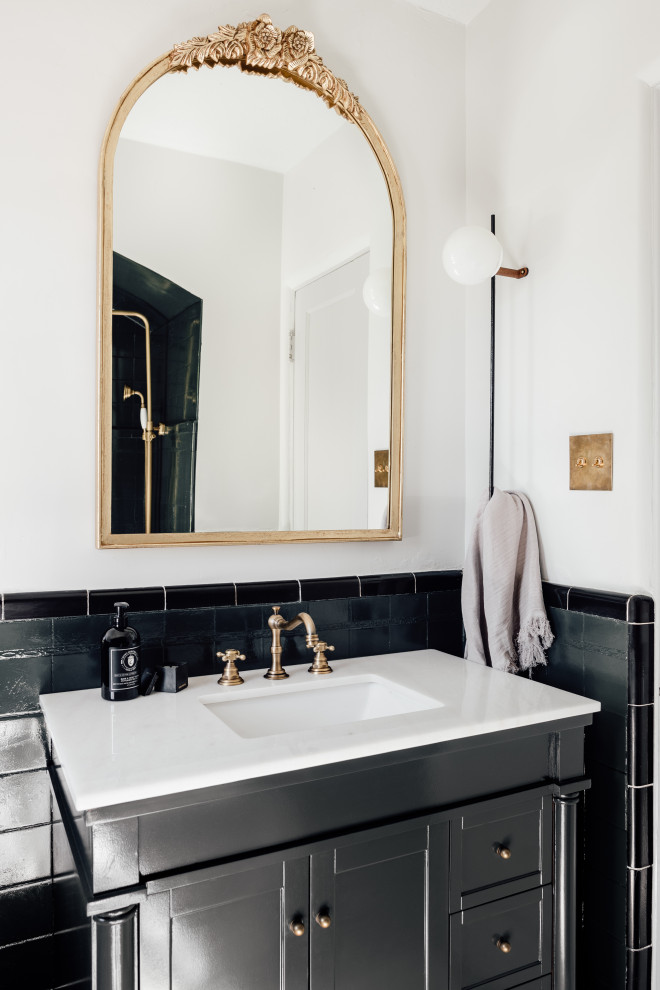 Ispirazione per una stanza da bagno classica con ante nere, piastrelle nere, pareti bianche, lavabo sottopiano, top bianco e ante con riquadro incassato