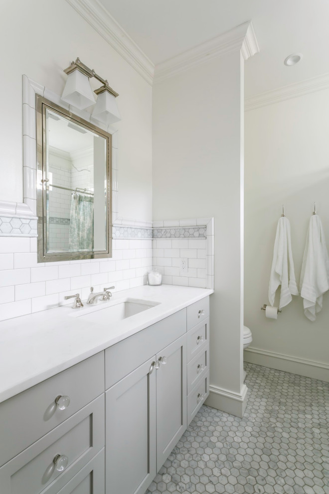 Cette photo montre une petite salle de bain chic avec WC à poser, un carrelage blanc, des carreaux de céramique, un mur blanc, un sol en marbre, un lavabo encastré, un plan de toilette en marbre, un sol blanc, un plan de toilette blanc, un placard avec porte à panneau encastré, des portes de placard grises, une baignoire en alcôve, un combiné douche/baignoire et une cabine de douche avec un rideau.