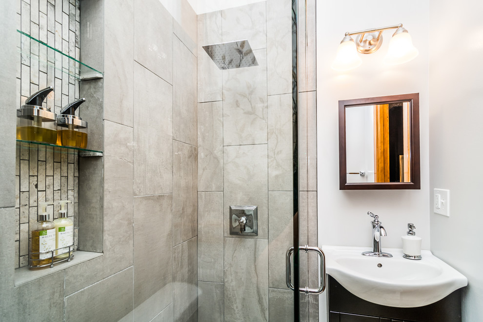 Inredning av ett klassiskt litet badrum med dusch, med en hörndusch, en toalettstol med separat cisternkåpa, grå kakel, porslinskakel, grå väggar och ett integrerad handfat