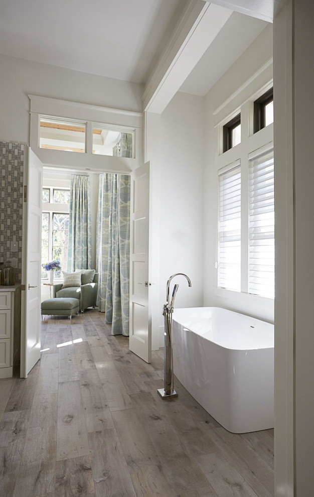 Diseño de cuarto de baño principal campestre con bañera exenta, paredes blancas, suelo de madera en tonos medios y suelo gris
