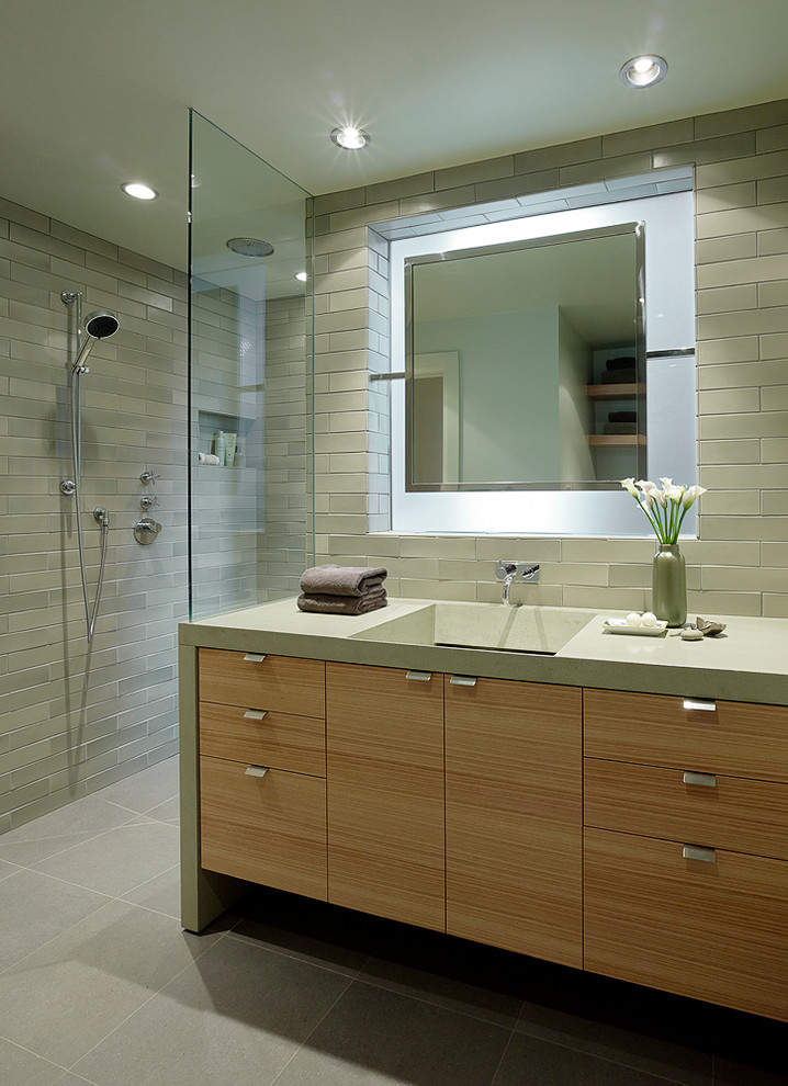 Cette image montre une salle de bain design en bois clair avec une grande vasque, un placard à porte plane, une douche ouverte, un carrelage gris, aucune cabine et un plan de toilette gris.
