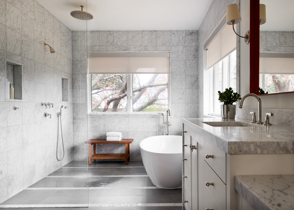 This is an example of a large traditional wet room bathroom in Dallas with white cabinets, a freestanding bath, a one-piece toilet, white tiles, marble tiles, white walls, porcelain flooring, a submerged sink, marble worktops, an open shower, white worktops and flat-panel cabinets.