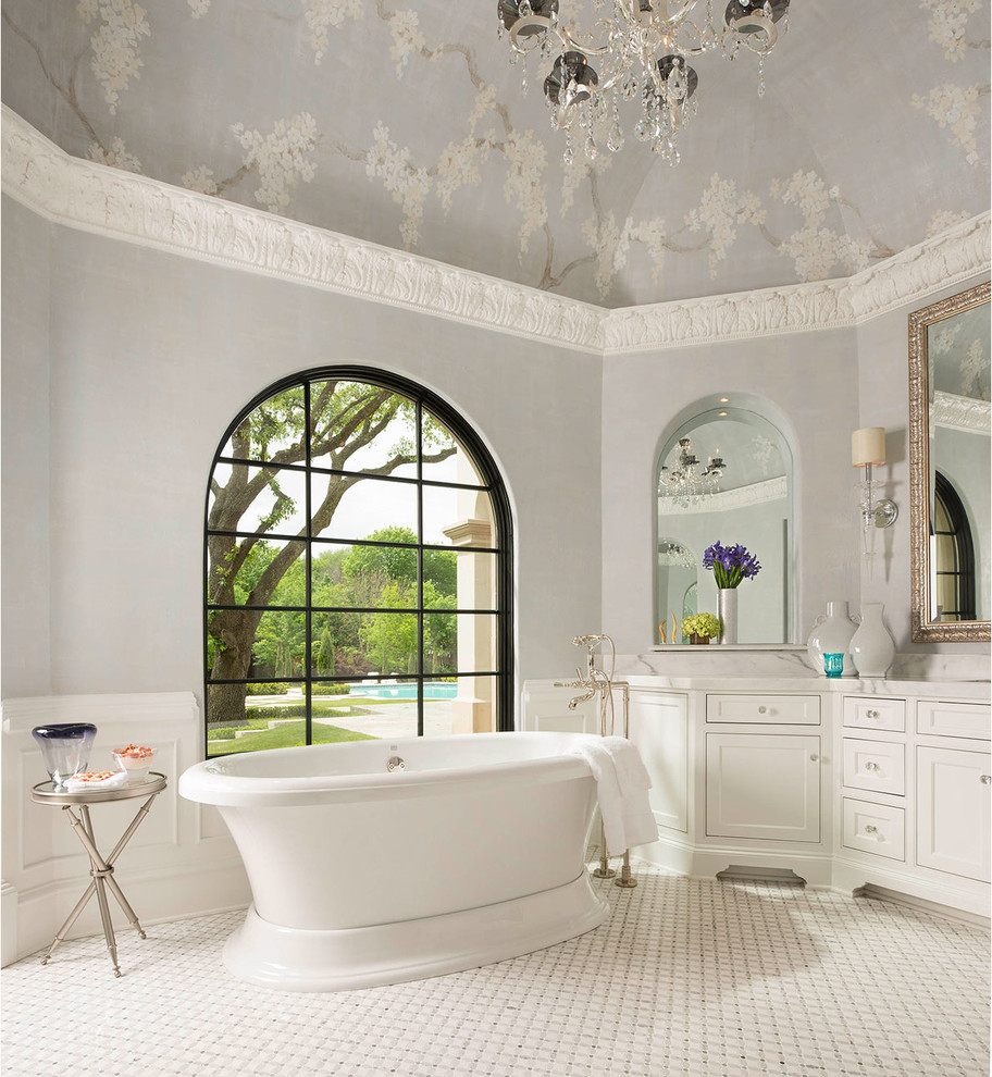 ダラスにあるラグジュアリーな広いトラディショナルスタイルのおしゃれなマスターバスルーム (落し込みパネル扉のキャビネット、白いキャビネット、置き型浴槽、グレーの壁、白い床、大理石の洗面台) の写真