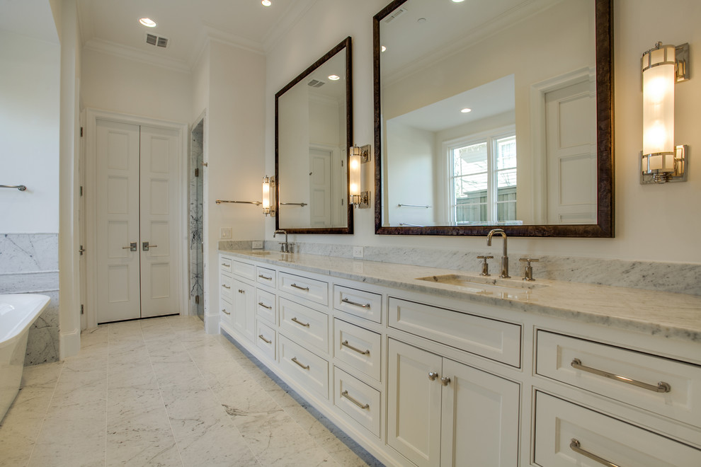 Idées déco pour une grande salle de bain principale classique avec un placard à porte affleurante, des portes de placard beiges, une baignoire indépendante, un mur beige, un sol en marbre, un lavabo encastré et un plan de toilette en marbre.
