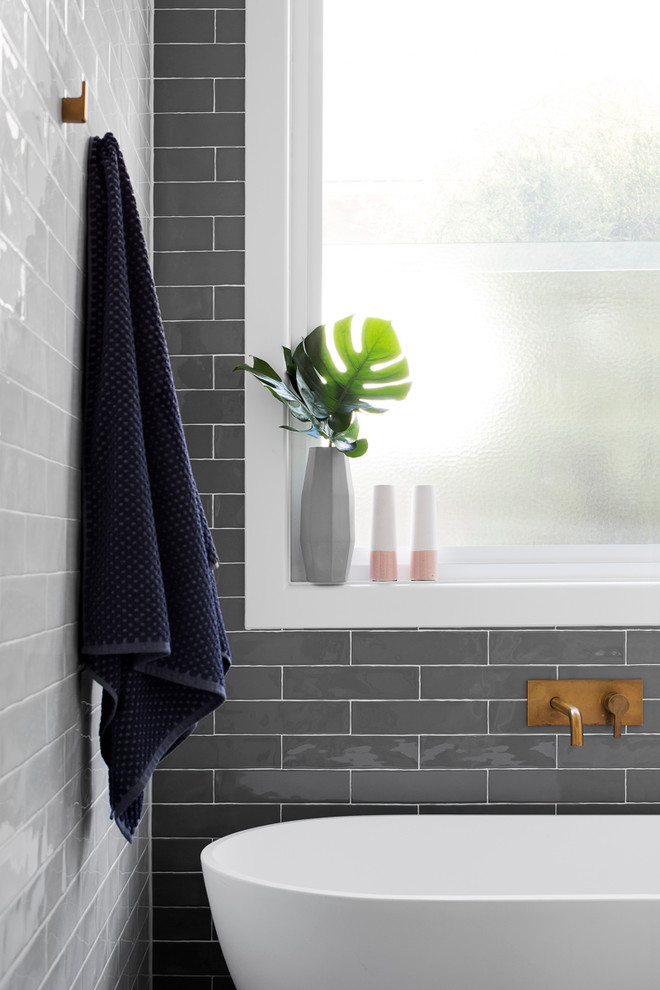 Modern inredning av ett stort grå grått en-suite badrum, med släta luckor, skåp i mellenmörkt trä, ett fristående badkar, en öppen dusch, en toalettstol med separat cisternkåpa, grå kakel, vit kakel, tunnelbanekakel, grå väggar, klinkergolv i keramik, ett fristående handfat, bänkskiva i betong, blått golv och med dusch som är öppen