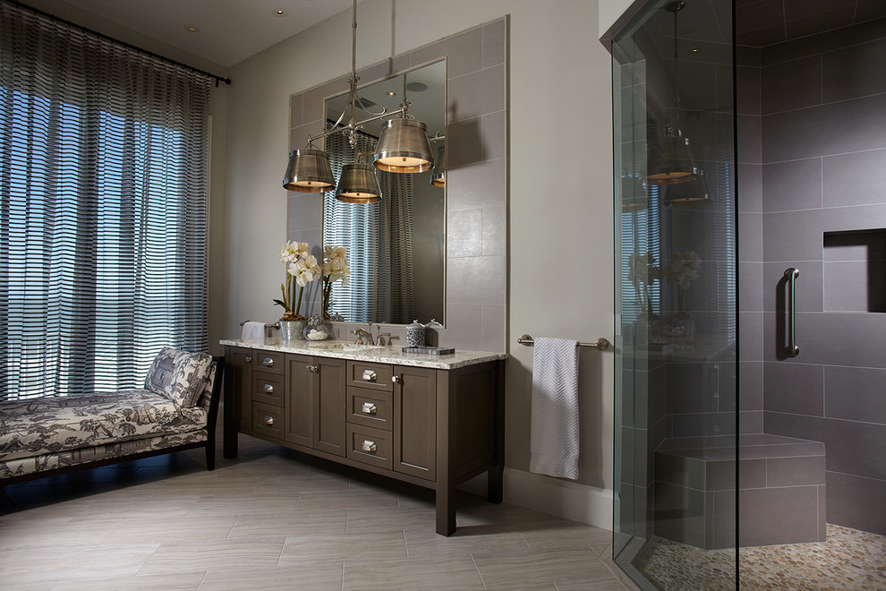 Inspiration for a world-inspired bathroom in Miami with a submerged sink, shaker cabinets, dark wood cabinets, a corner shower, grey tiles and grey walls.