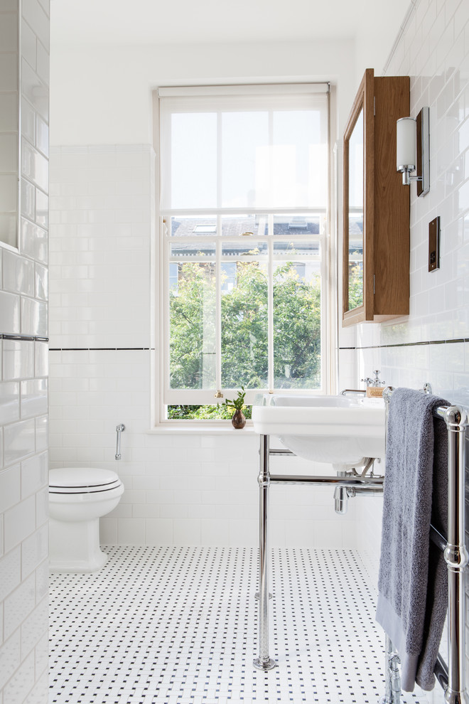 Klassisches Badezimmer mit Waschtischkonsole, Wandtoilette mit Spülkasten, Metrofliesen, weißer Wandfarbe und schwarz-weißen Fliesen in London