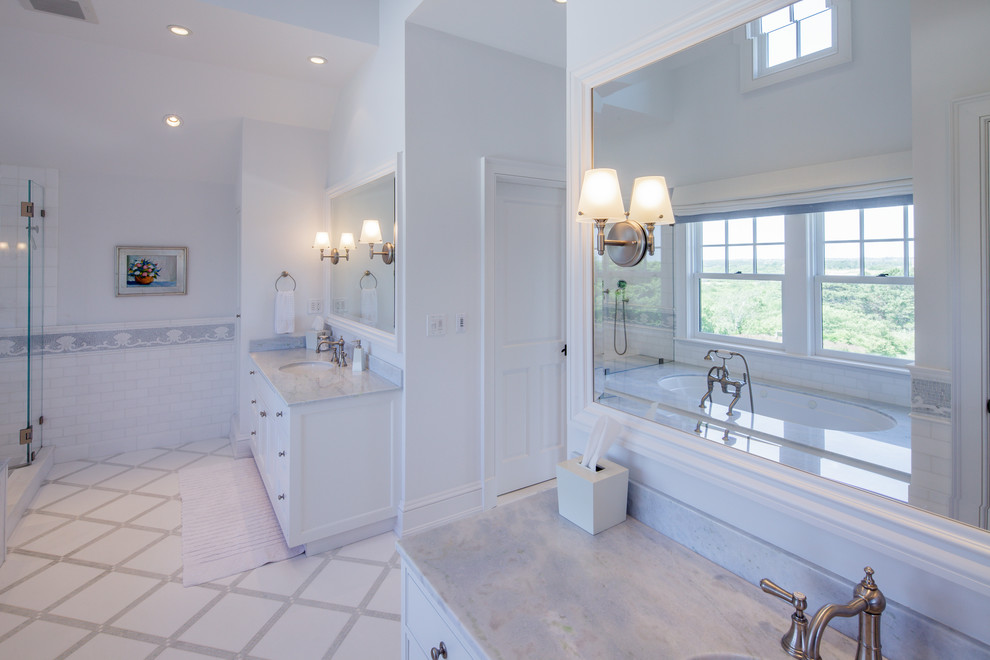Idée de décoration pour une salle de bain principale tradition avec un placard à porte affleurante, des portes de placard blanches, un carrelage blanc et un plan de toilette en marbre.