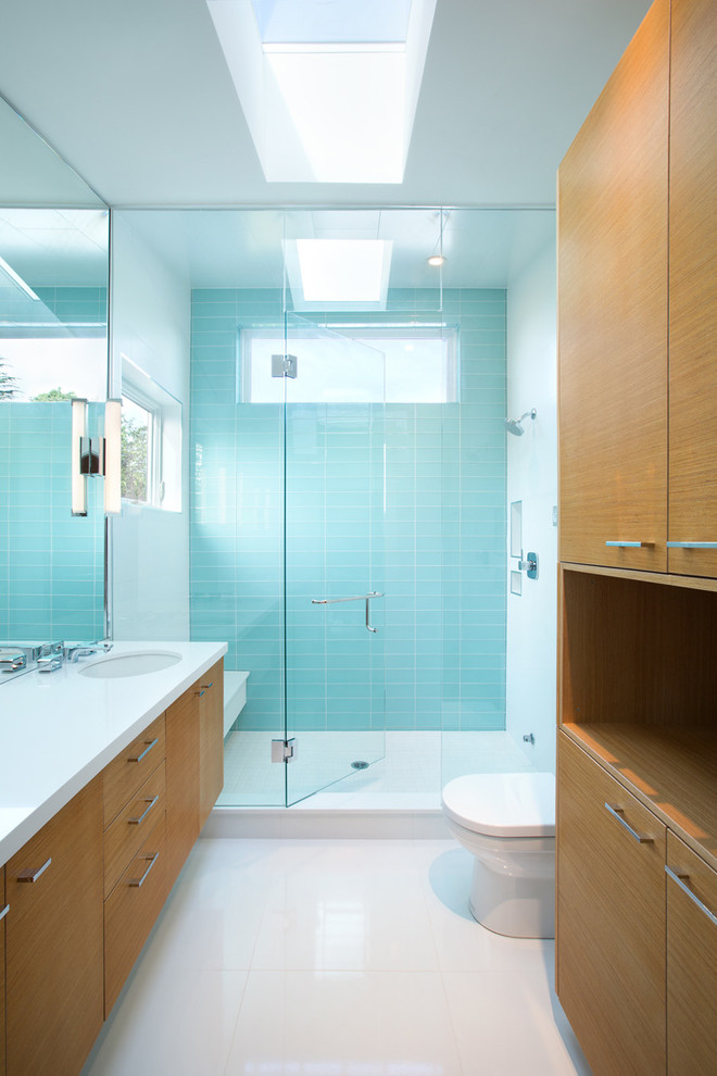Esempio di una stanza da bagno contemporanea con lavabo sottopiano, ante lisce, ante in legno scuro, doccia alcova, piastrelle blu e piastrelle di vetro