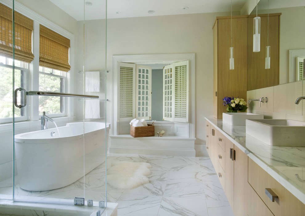 Trendy freestanding bathtub photo in Boston with marble countertops and a vessel sink