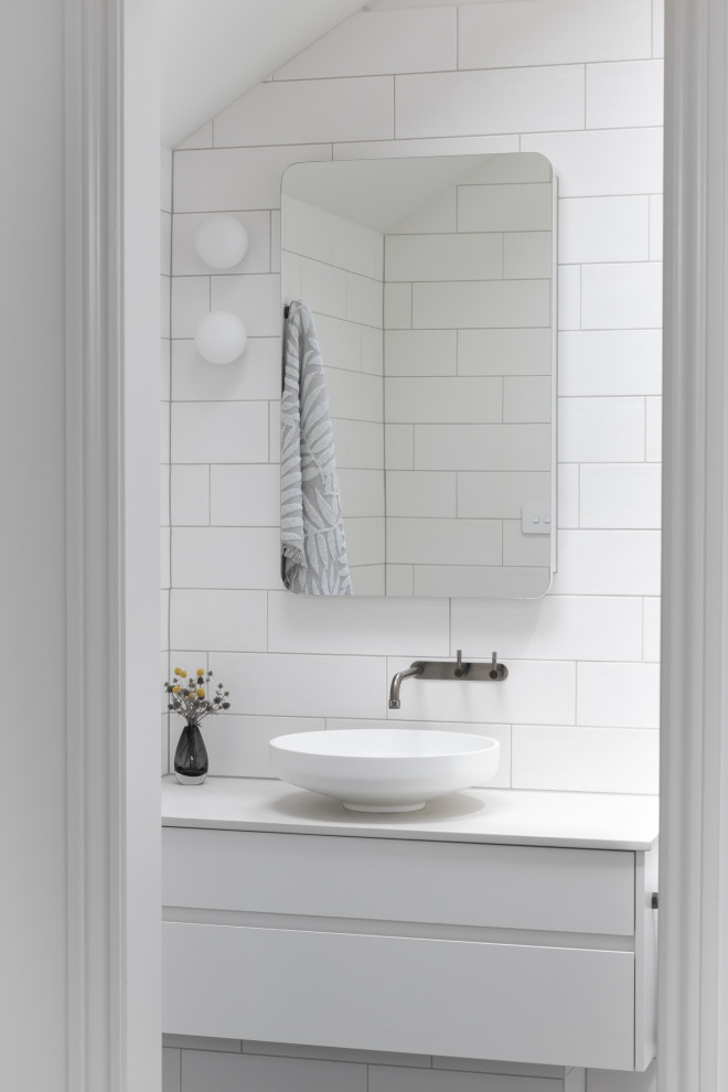 Immagine di una stanza da bagno contemporanea con ante lisce, ante bianche, piastrelle bianche, pareti bianche, lavabo a bacinella, top bianco e mobile bagno sospeso
