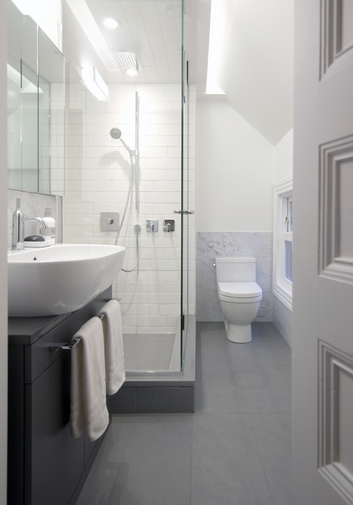 This is an example of a contemporary bathroom in Vancouver with flat-panel cabinets, a corner shower, a two-piece toilet and a console sink.