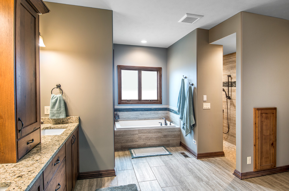 Ejemplo de cuarto de baño principal de estilo americano con lavabo bajoencimera, puertas de armario de madera oscura, encimera de granito, bañera encastrada, baldosas y/o azulejos beige y paredes beige