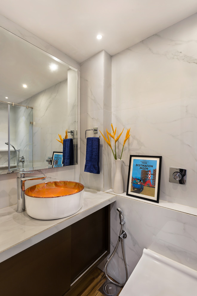 Photo of a contemporary shower room bathroom in Mumbai with flat-panel cabinets, brown cabinets, a wall mounted toilet, white tiles, white walls, a vessel sink, brown floors and white worktops.
